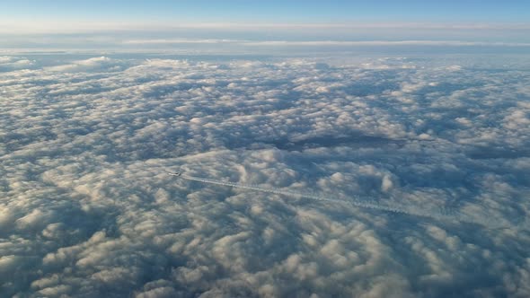 Incredible view from the cockpit of an airplane flying high above the clouds leaving a long white co alt