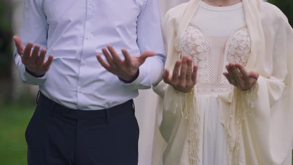 Unrecognizable Muslim Couple Praying Outdoors in Spring Summer Garden alt