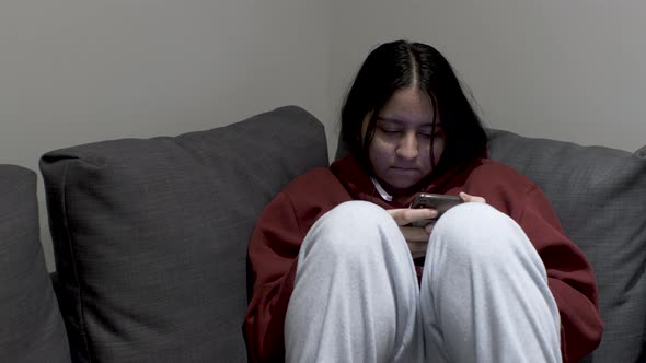 A young teenage Indian girl deeply engrossed in her digital world as she scrolls social media sittin alt