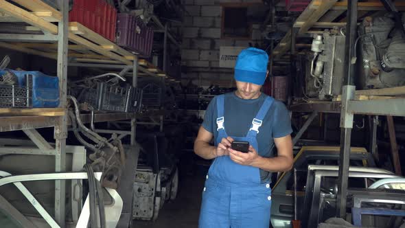 employee of auto disassembly, completes or checks car parts from tablet computer alt