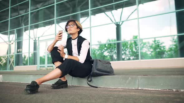 Young Beautiful Businesswoman Sitting on Street Speaking on Phone Business Centre Background alt
