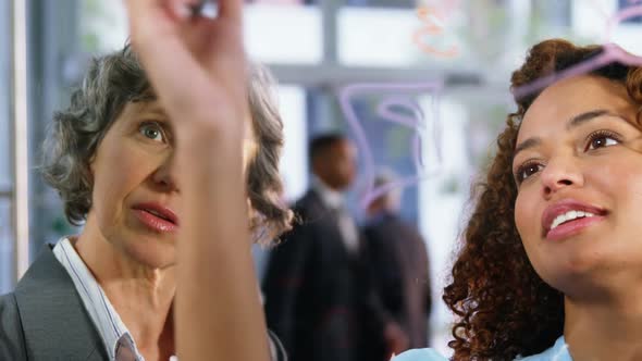 Business colleagues talking while writing on glass window alt