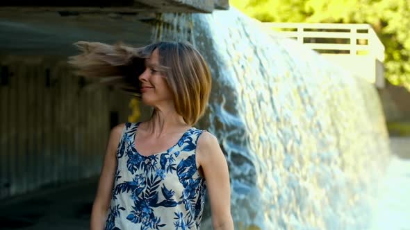 Super Slow Motion Of A Girl Shaking Hair From Side To Side Standing Near The Waterfall In City Park