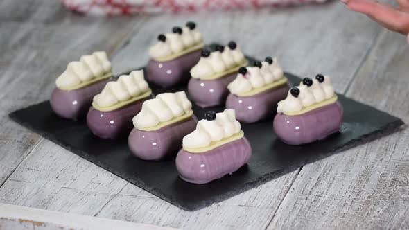 Confectioner decorates mousse cake with a blueberries Production of glazed desserts alt