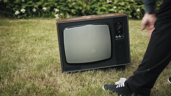 Man Turns on Old Retro TV Set Standing on Grass