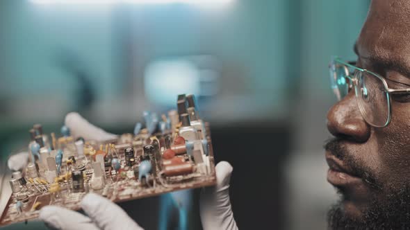 Black Engineer Examining Circuit Board alt