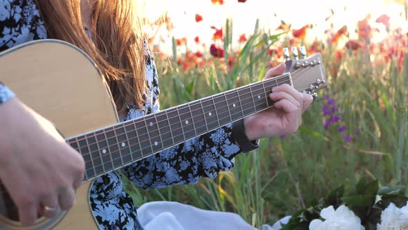 A woman enjoys playing her guitar in the sunlight on a sunset day in nature.