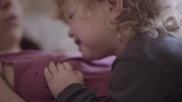 a disgruntled child lies on his mother's chest alt