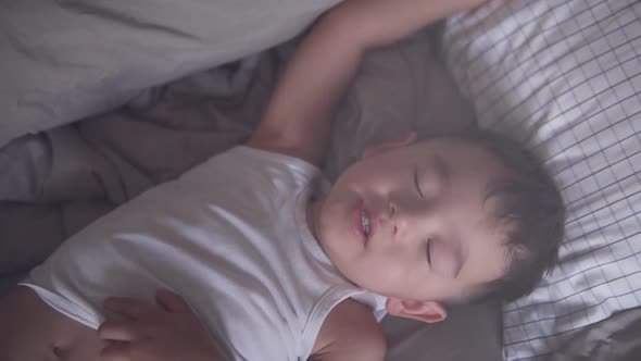 High angle shot of a little two years old Asian toddler dreaming and moving while sleeping maybe hav alt