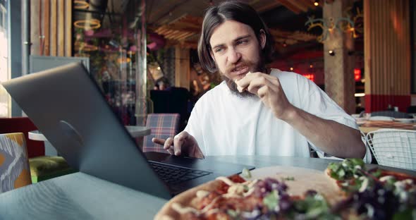 Focused Male With Laptop Eating Pizza