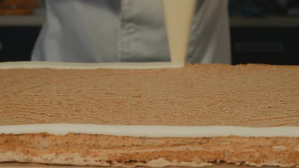 Baked Sponge Cake for the Entire Frame. A Cool Pastry Chef Applies Cream Around the Perimeter of the alt