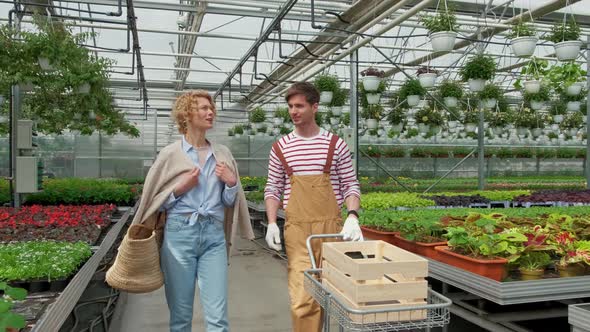 Blonde Woman Housewife Buys a Plant in the Nursery and Talks to the Gardener alt