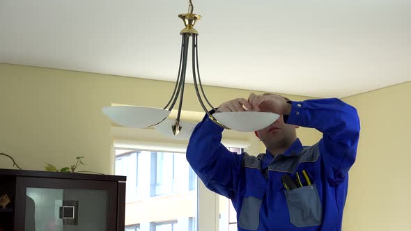 Experienced Electrician Changing Light Bulbs at Client's Home