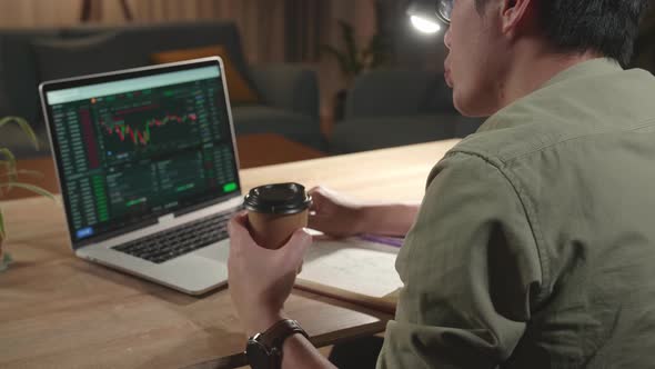 Asian Man Trader Investor Sitting In A Wheelchair And Drink Coffee While Trading Cryptocurrency alt