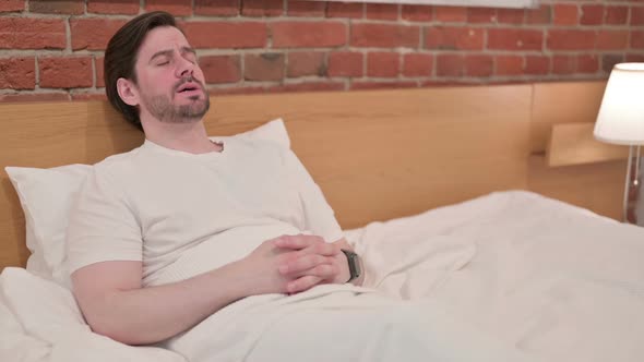 Casual Young Man Feeling Worried While Sitting in Bed alt