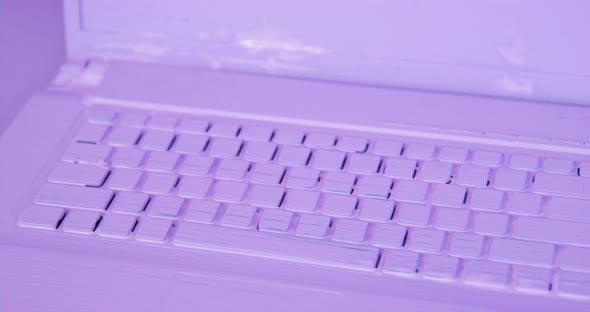 The Camera Moves Along the Keyboard of Laptop Which is Completely Painted Purple As is Table on