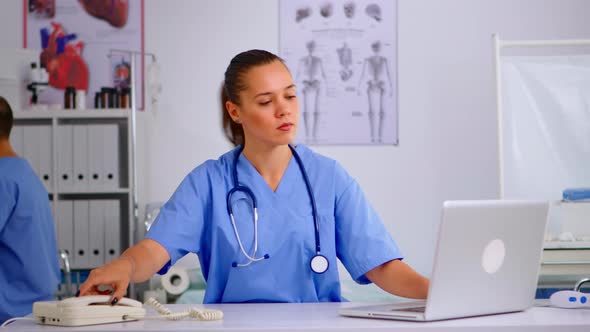 Woman Nurse Answering Telephone in Hospital Reception alt