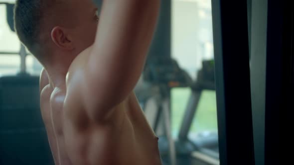 Athletic Man Engages in Lat Pulldowm Machine in the Gym alt