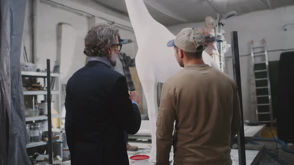 Men Discussing Giraffe Statue Production alt