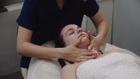 Woman Massagist Applying Cream on the Neck and Face of Her Female Client After the Massaging alt