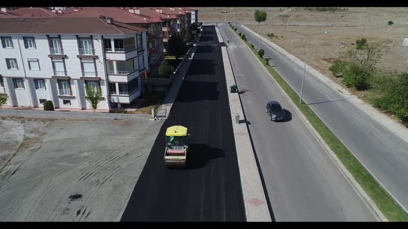 A Large Yellow Steamroller Flatten Hot Asphalt. Builds A New Road