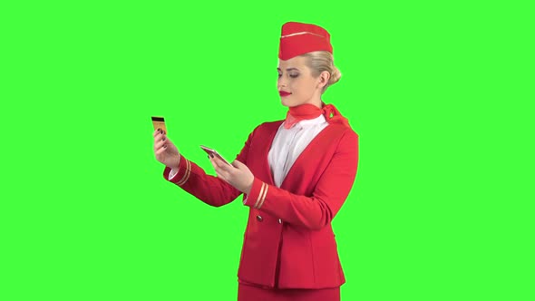 Stewardess Girl in a Red Suit Is Picking Up the Credit Card Code. Green Screen alt