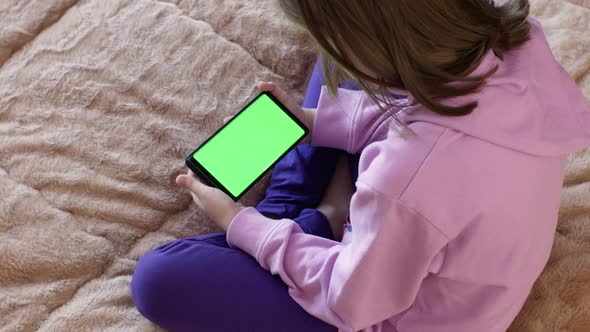 Girl Holding a Smartphone with a Green Screen and Touching the Screen