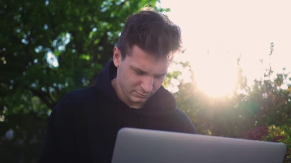 Guy Works at Laptop in City Park alt