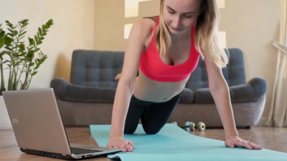 Young Fit Woman in Sportswear Watching Online Video with Fitness Exercises on Laptop and Doing Push alt