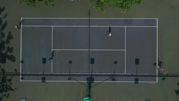 Aerial top down view of men's doubles tennis game showing full court. Serve is returned and winning alt