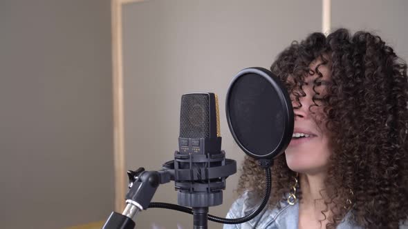 A Fashionable Energetic Singer Sings Into a Microphone in a Recording Studio alt