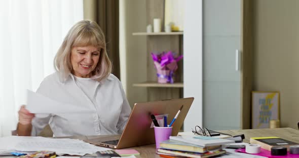Old Retired Woman Working at Home in Quarantine Online Talking at a Business Conference Via Laptop alt