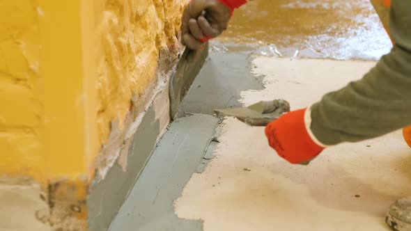 Hands Use a Spatula to Putty the Protrusion of the Wall with the Floor