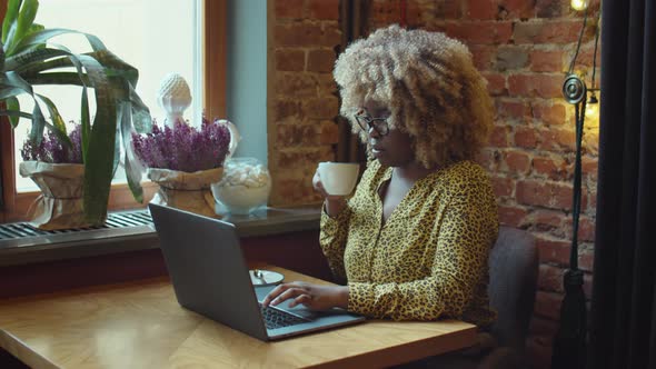 African American Woman Having Coffee and Working Online in Cafe alt