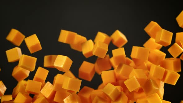 Super Slow Motion Shot of Flying Cheddar Cheese Cubes on Black Background at 1000 Fps alt
