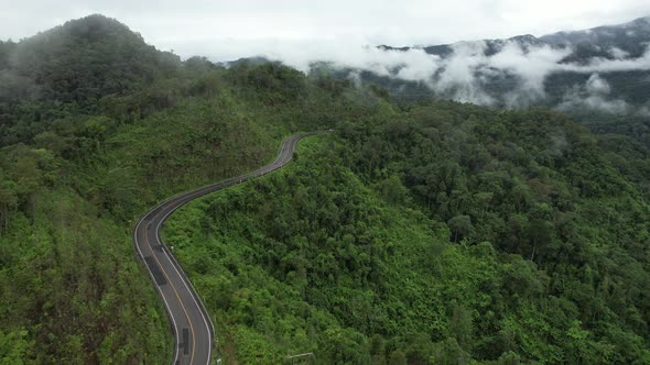 Aerial view of mountain road through tropical forest in countryside of Asia by drone