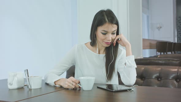 Yawning Bored Girl Using Tablet and Drinking Coffee in a Cafe alt