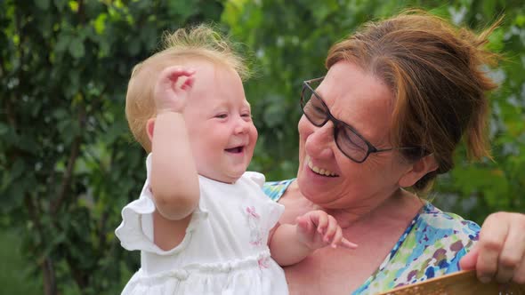 Grandmother waving with chine or japan fan on baby girl. Games with toddler. Good emotions concept alt