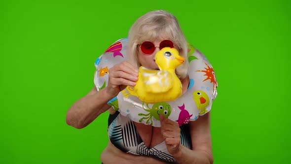 Senior Woman Tourist in Swimsuit Dancing Celebrating Playing with Inflatable Duck Toy Rubber Ring alt
