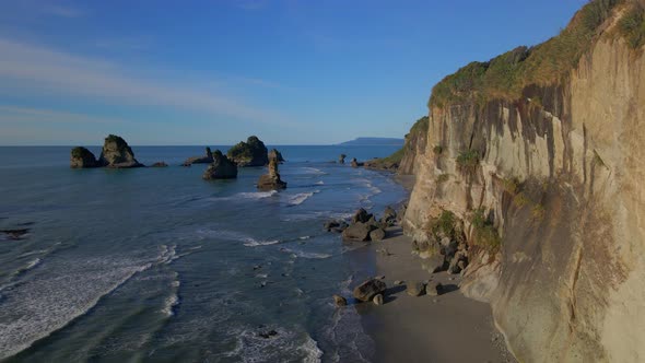 Aerial view of steep rocky cliffs with rugged wild coastline by Tasman sea in New Zealand alt