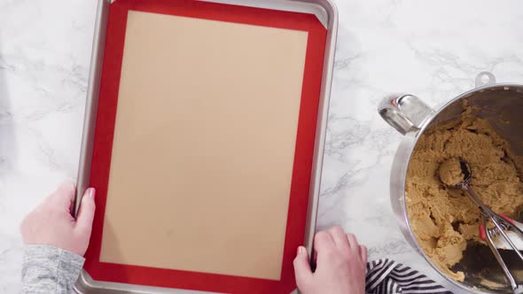 Flat lay. Step by step. Scooping peanut butter cookies dough with dough scooper into the baking shee alt