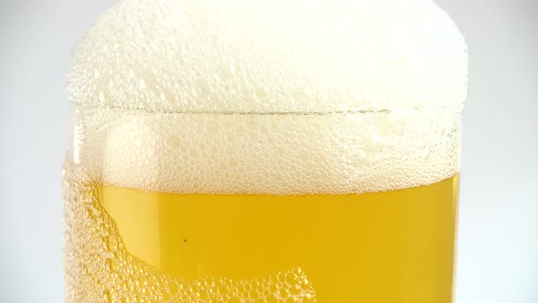 Glass of beer with bubbles and thick white foam alt