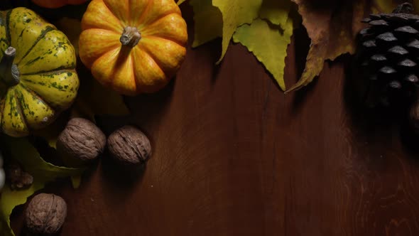 Rustic Still Life with Walnuts and Pumpkins Lying on a Table Next to Apples and Cones Among Foliage alt