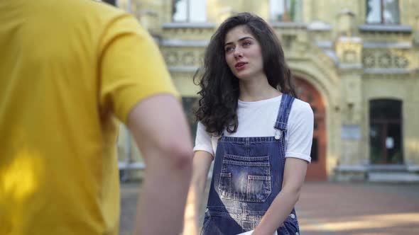 Positive Pretty Woman Bumping Fists with Groupmate Standing on University Yard in the Morning alt