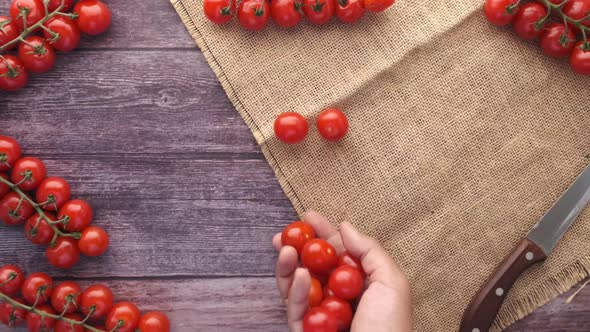 Hand Putting Red Color Cherry Tomato on Table alt