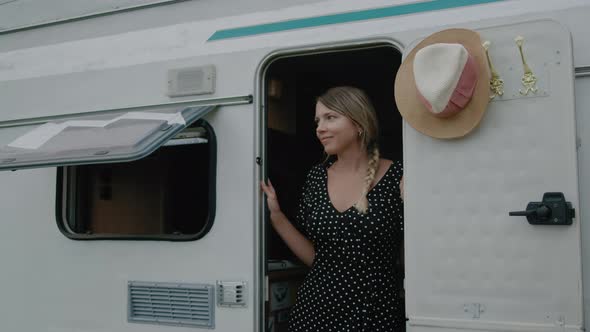 Smiling woman enjoyng vacation and standing in motor home RV campervan. alt