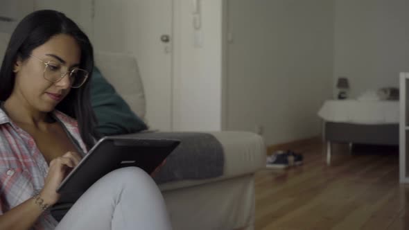 Focused Young Hindu Businesswoman in Eyeglasses Working with Tablet at Hotel Room. alt