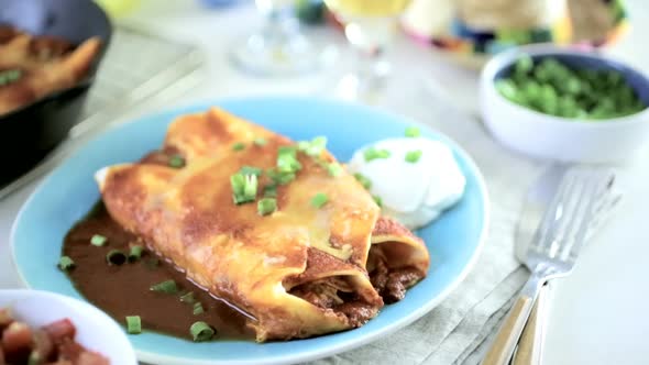 Dinner table with Chicken enchiladas garnished and craft beer. alt