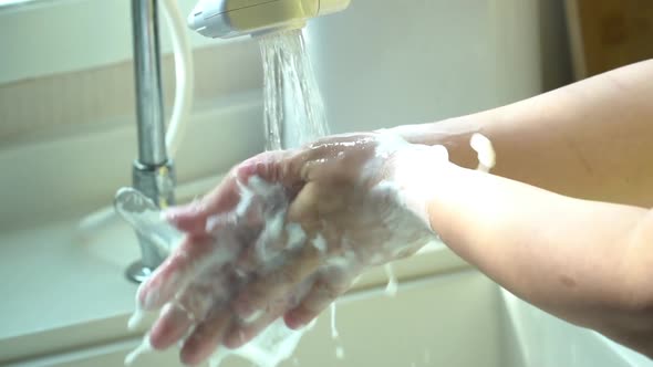 Hands Of Woman Wash Their Hands In A Sink With Foam alt