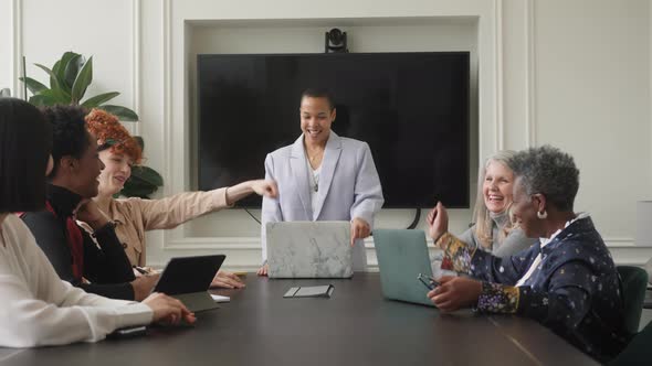 Slow motion of multi ethnic mixed age range businesswomen fist bumping in creative meeting alt